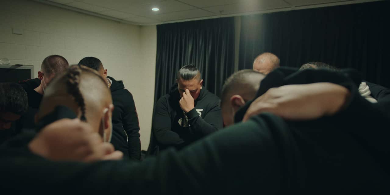 A group of men huddled together with their heads bowed.