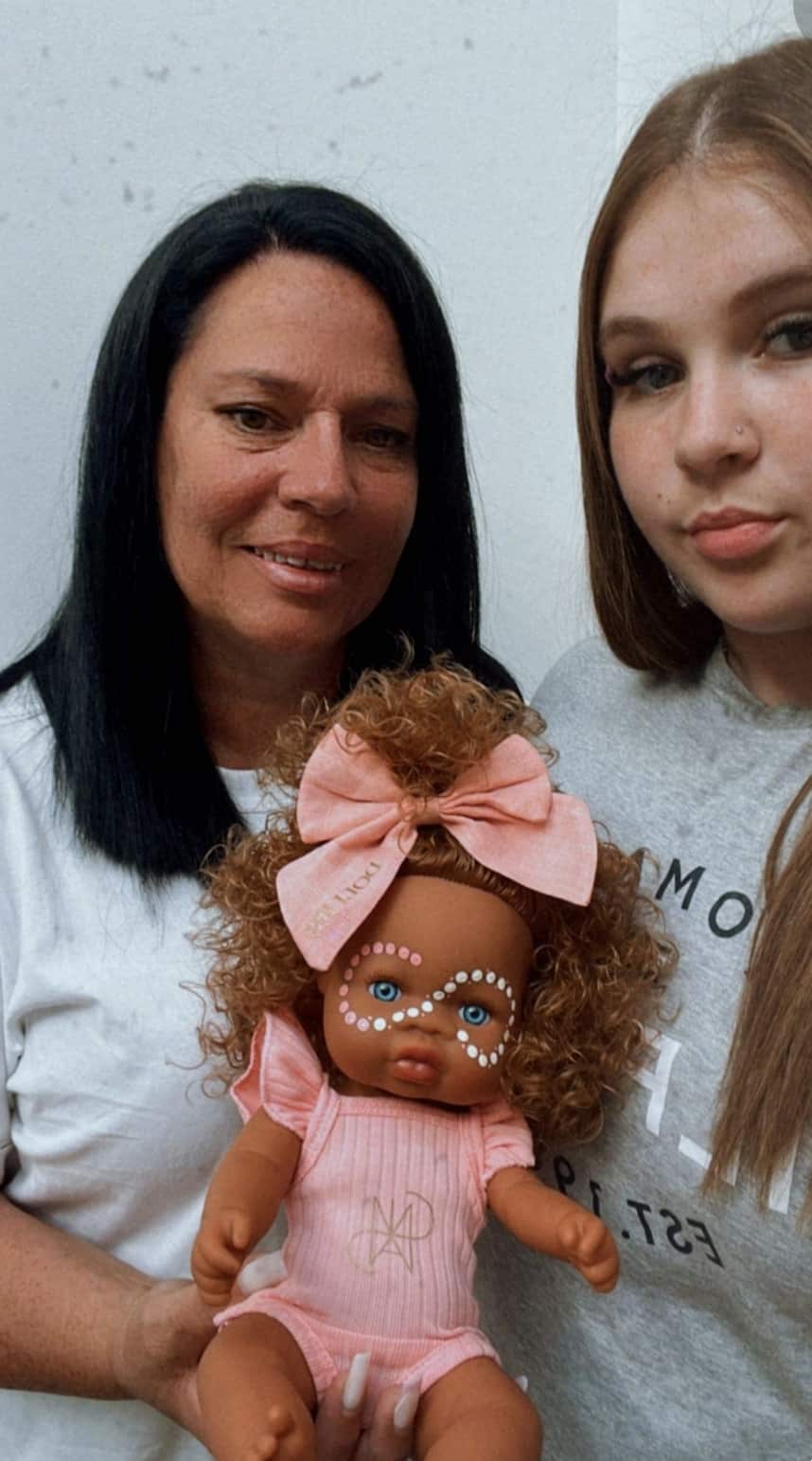 A mother and daughter hold up a doll. 