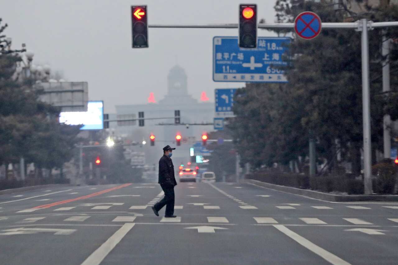 A man is seen walking across an empty road.
