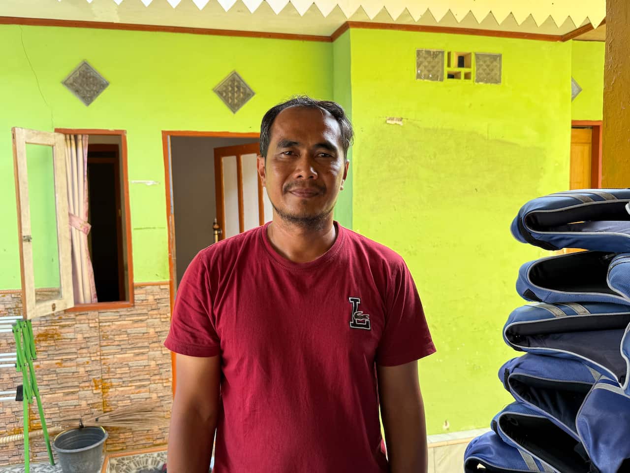 Edi Mulyono stands in front of his home on Pari Island. 