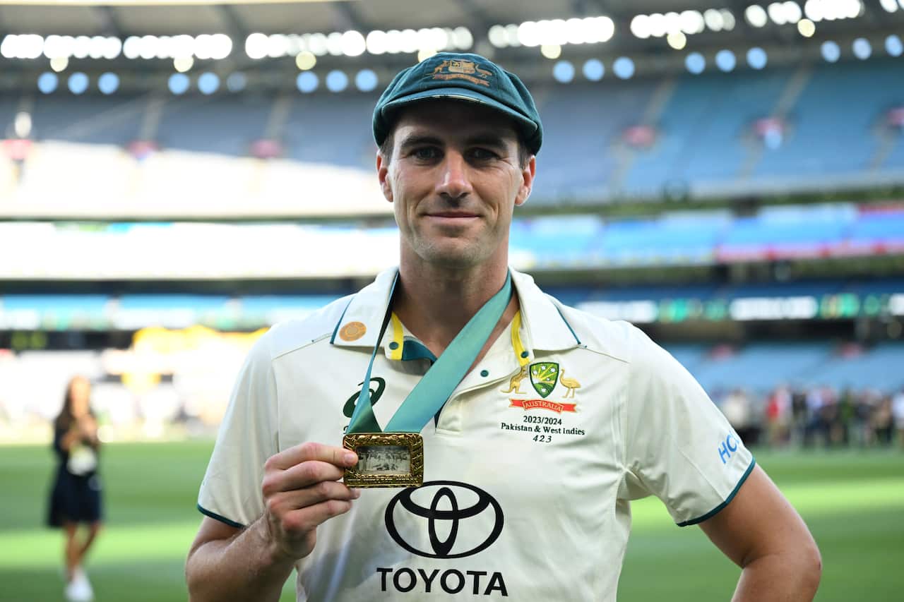 A cricketer poses with a medal