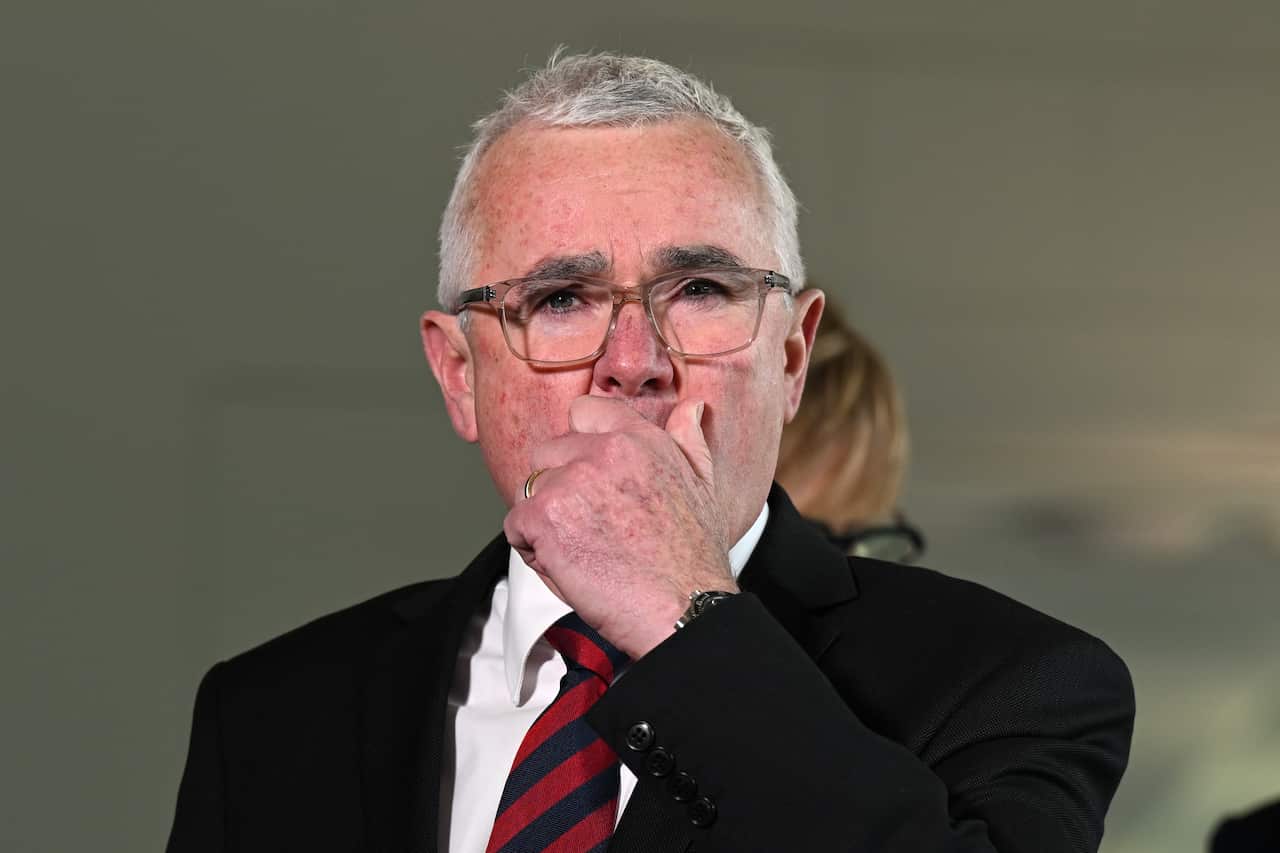 MP Andrew Wilkie, holding his hand up to his mouth about to address media.