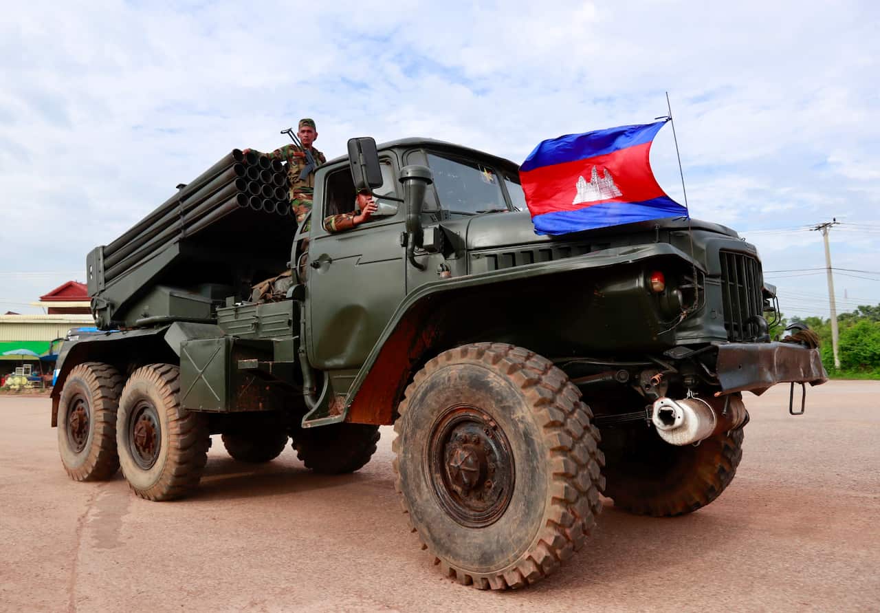 A large army truck painted green with rocket-launching equipment on the back. It has a flag of a large red stripe with a dark blue stripe above and below and a white temple in the centre 
