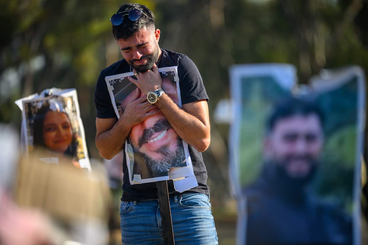 A man cries while hugging a portrait of his brother during a memorial.