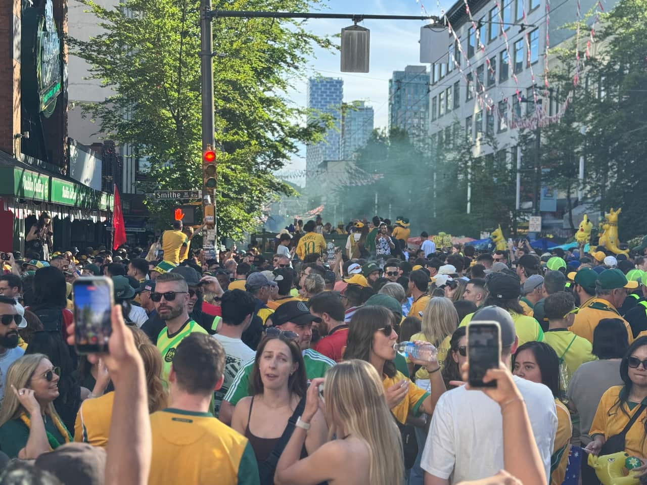 Football fans wearing green and gold jerseys shutting down a city street.