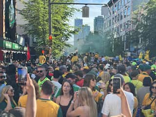 Football fans wearing green and gold jerseys shutting down a city street.