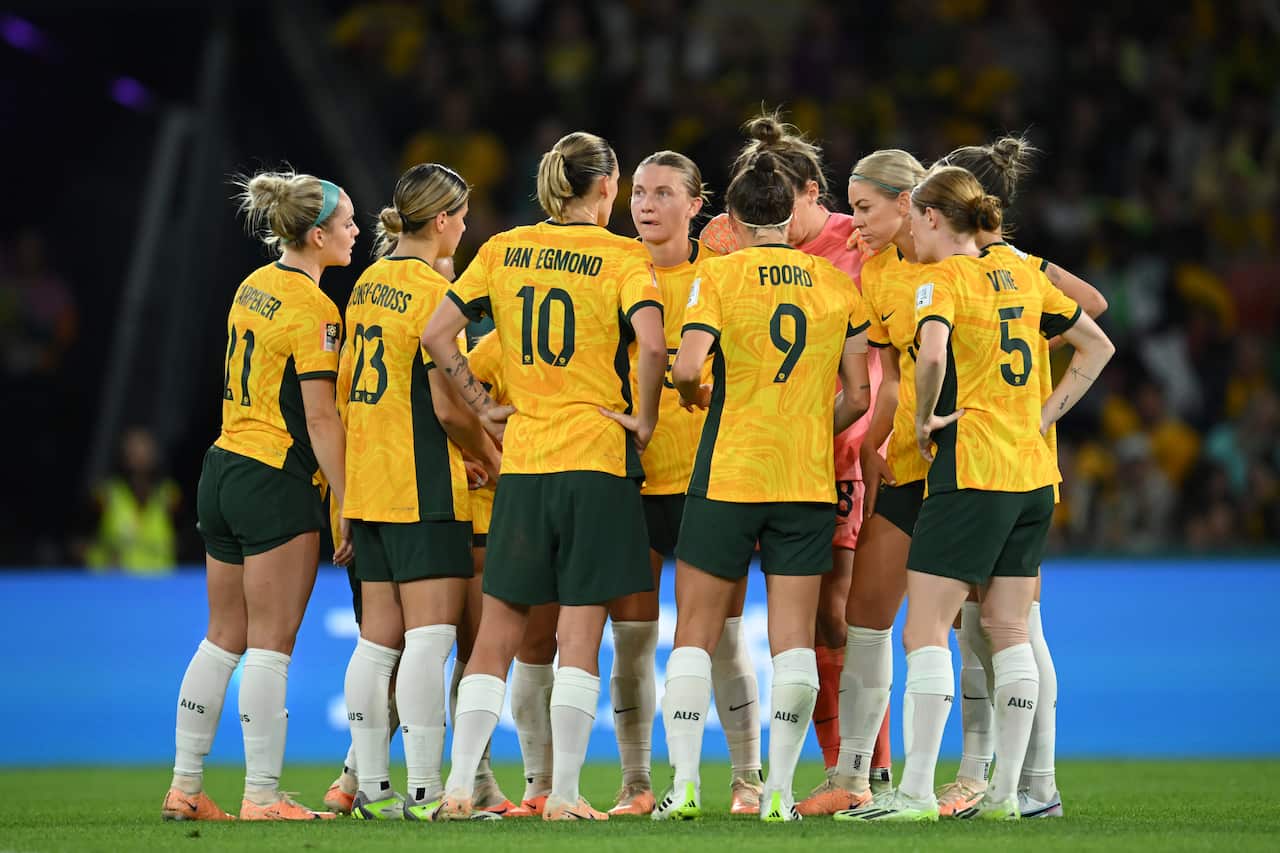 A group of women's football players huddle around one another.