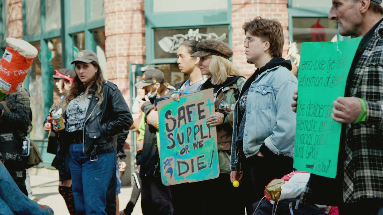 Rally attendees stand holding placards 
