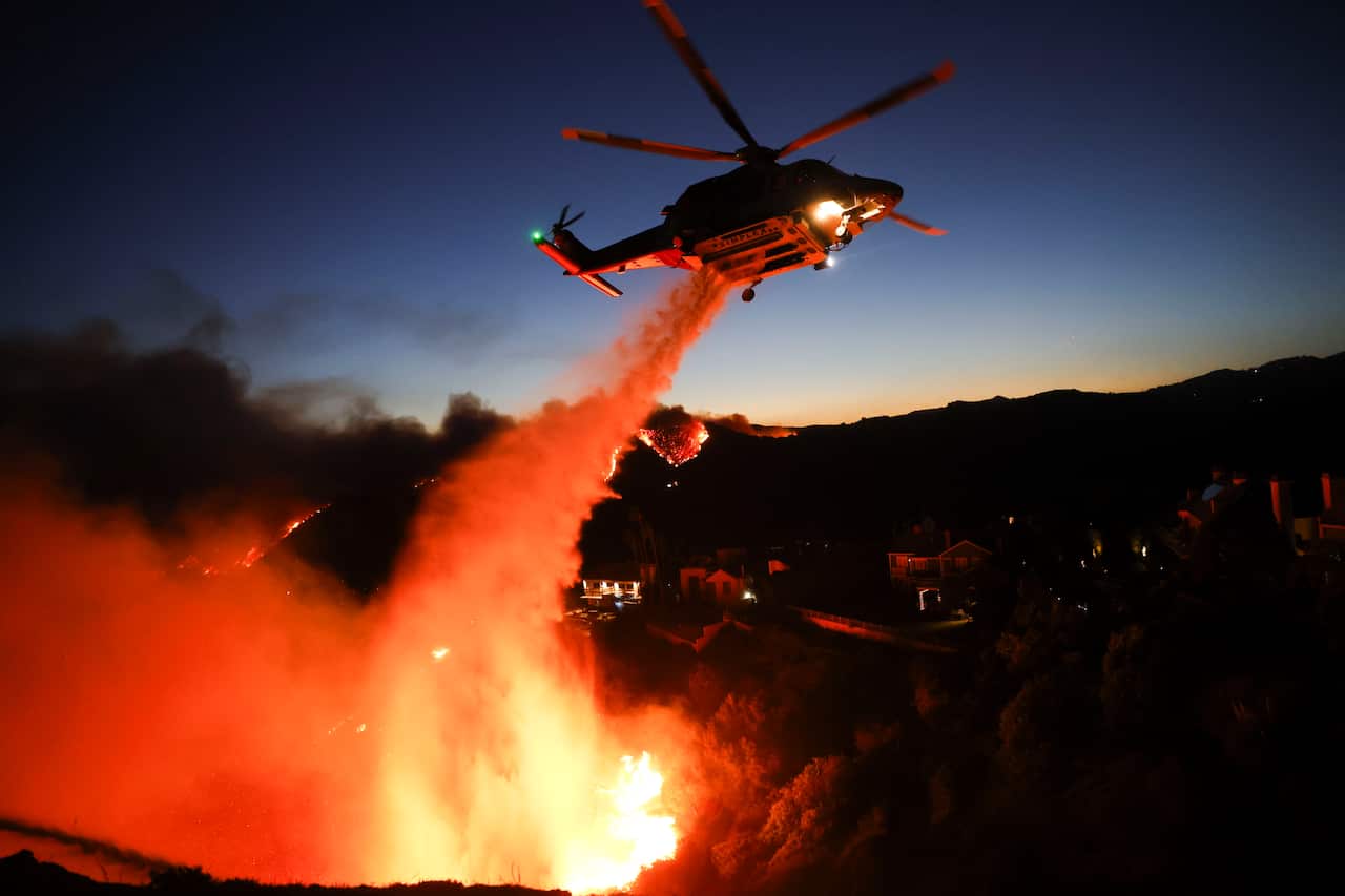 A helicopter waterbombing a wildfire.