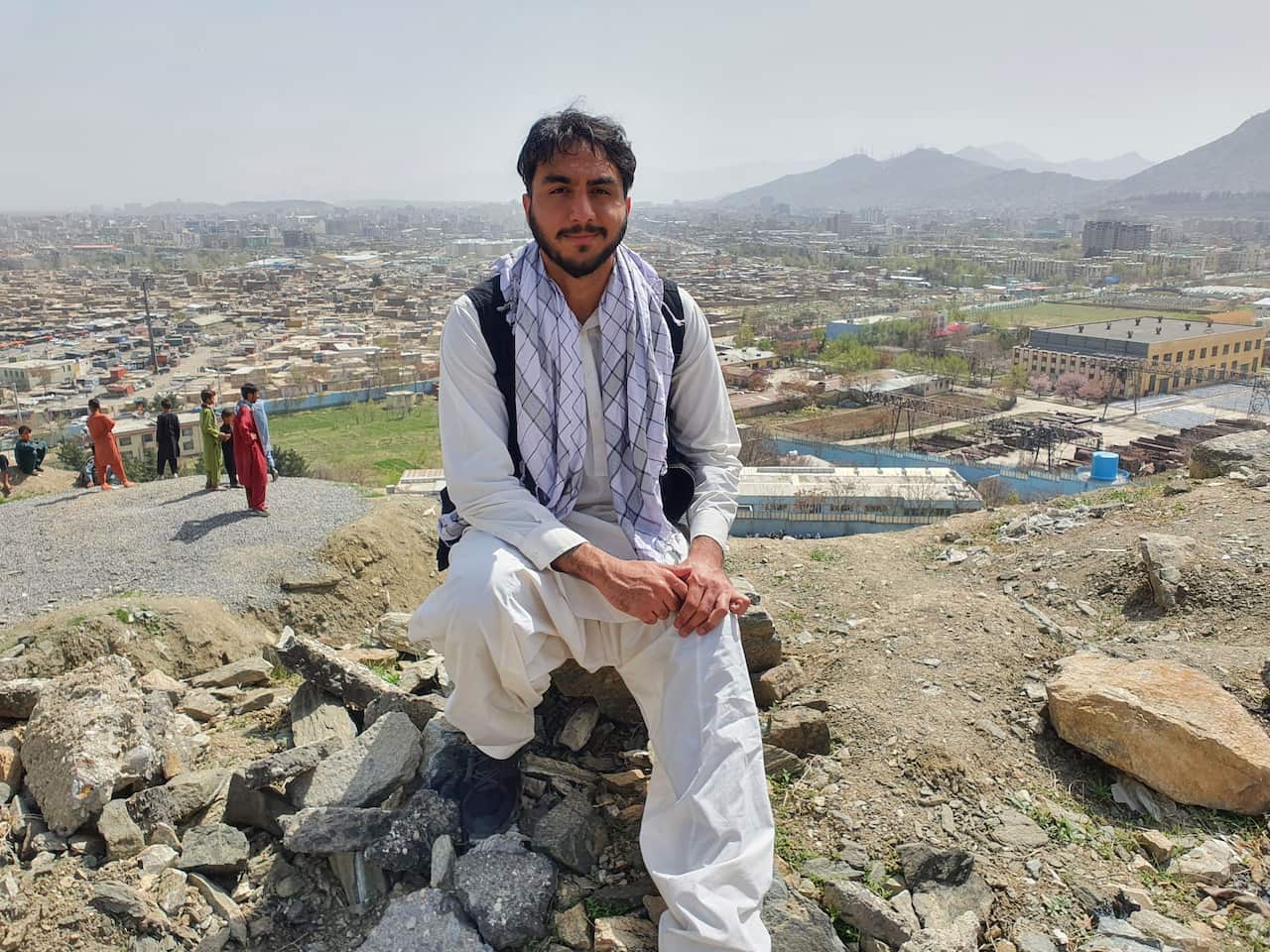 A man sits on top of a hill