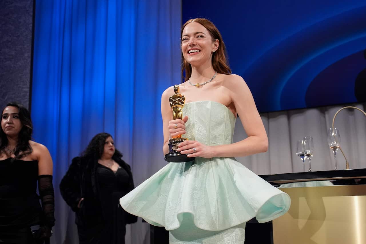 A woman wearing a dress poses for a photo with an award. 