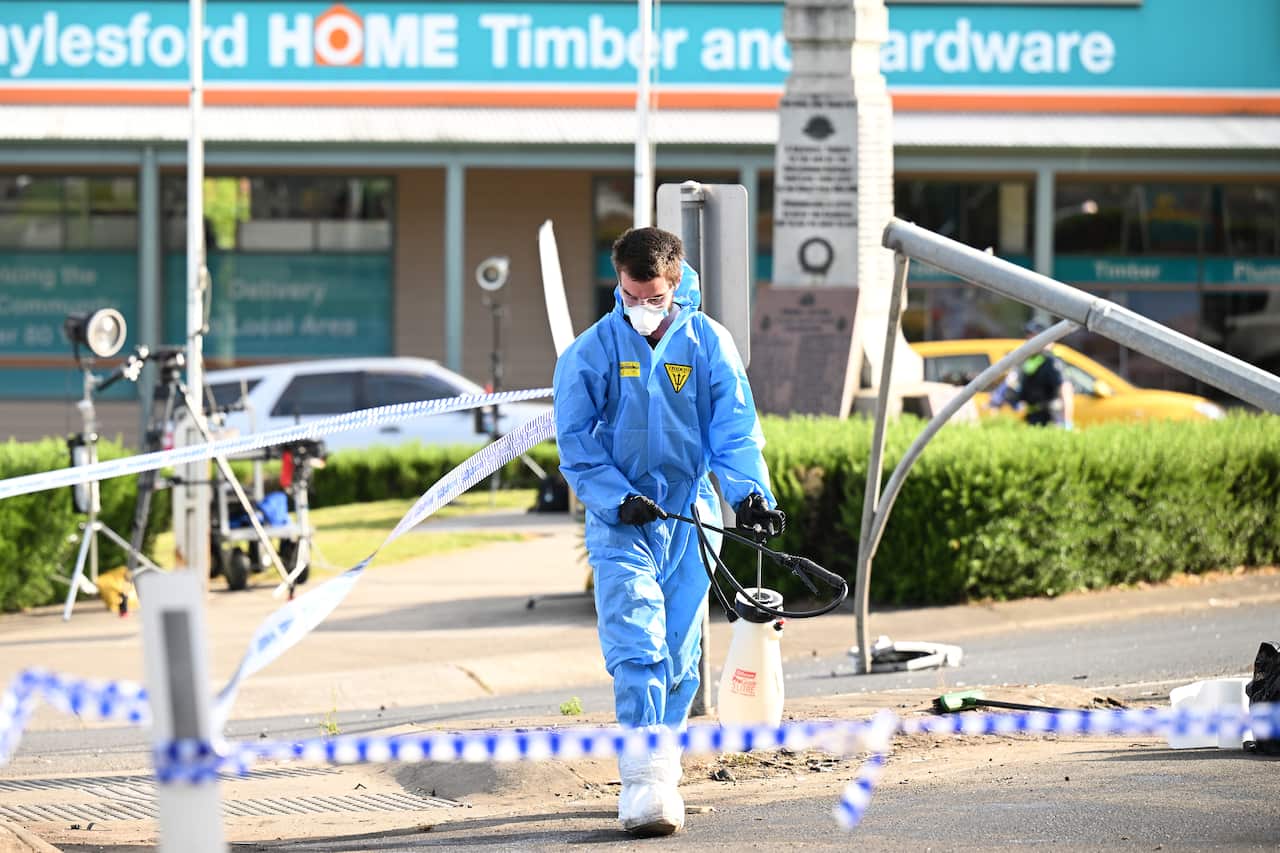 A cleaner works through the scene of a car crash.