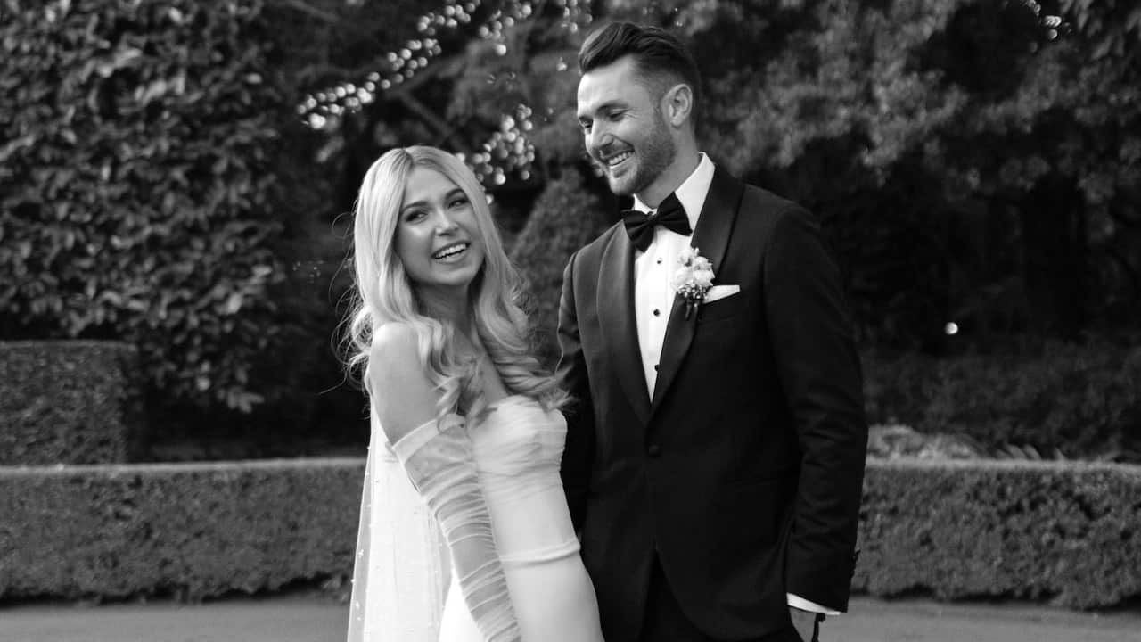 black and white wedding photo of a bride and groom in front of a hedge