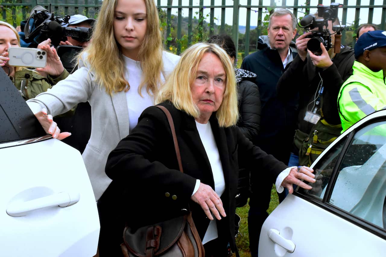 An older blonde woman get out of a white car