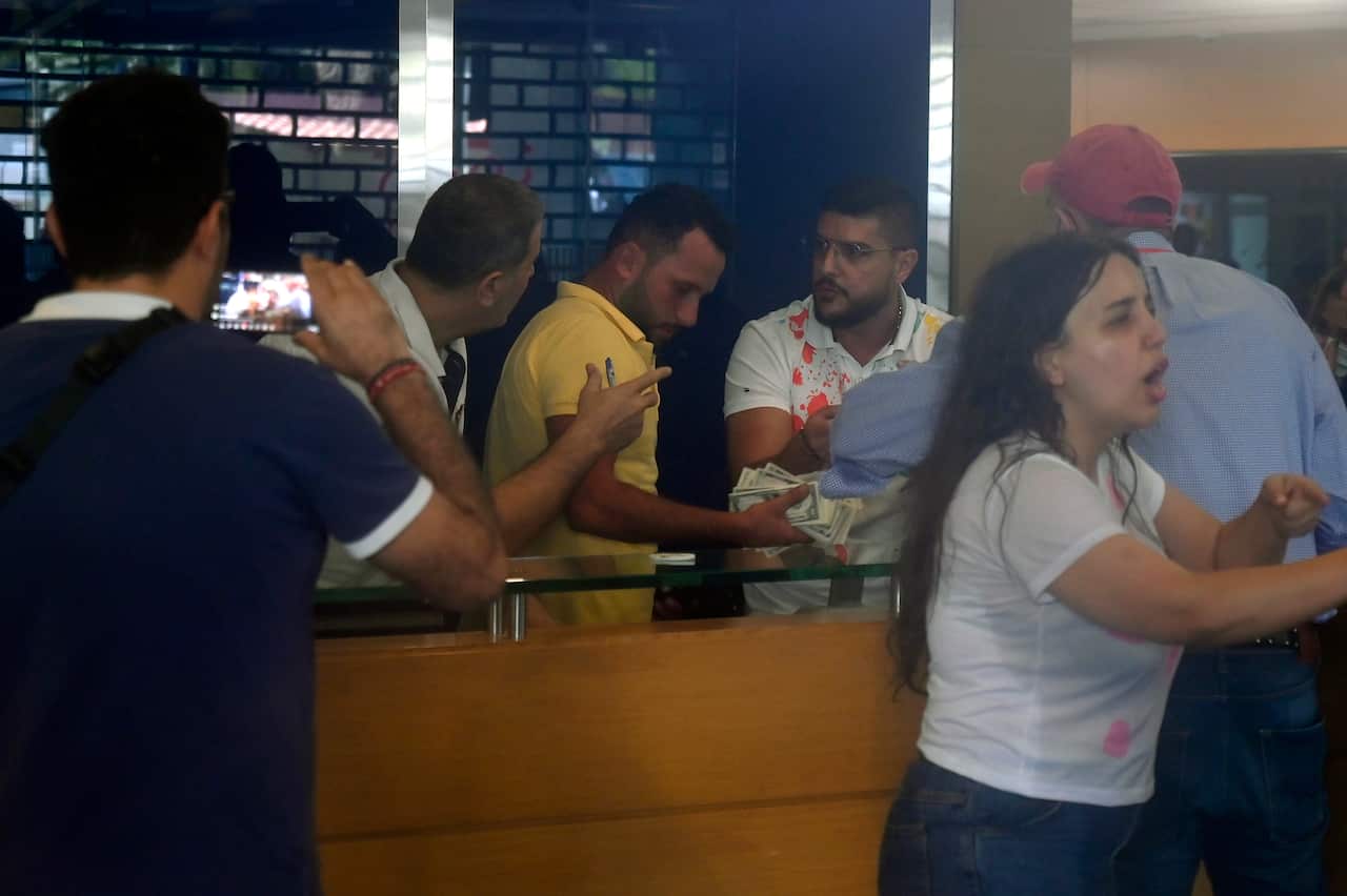 A man carried banknotes in a bank surrounded by people