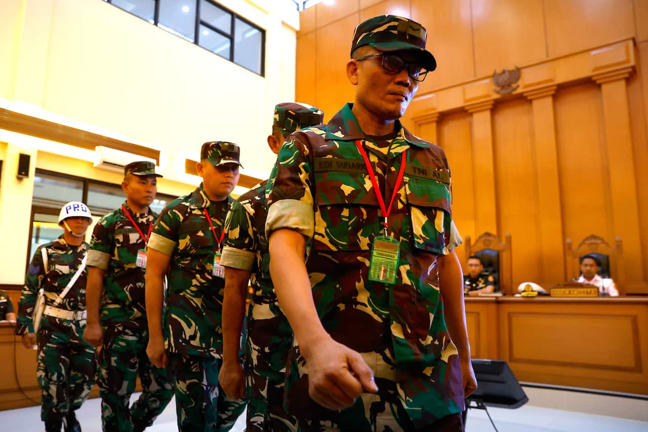 Five men in military uniform walk into a courtroom.