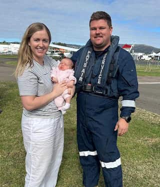 A man, woman, and their baby pose for a photo.