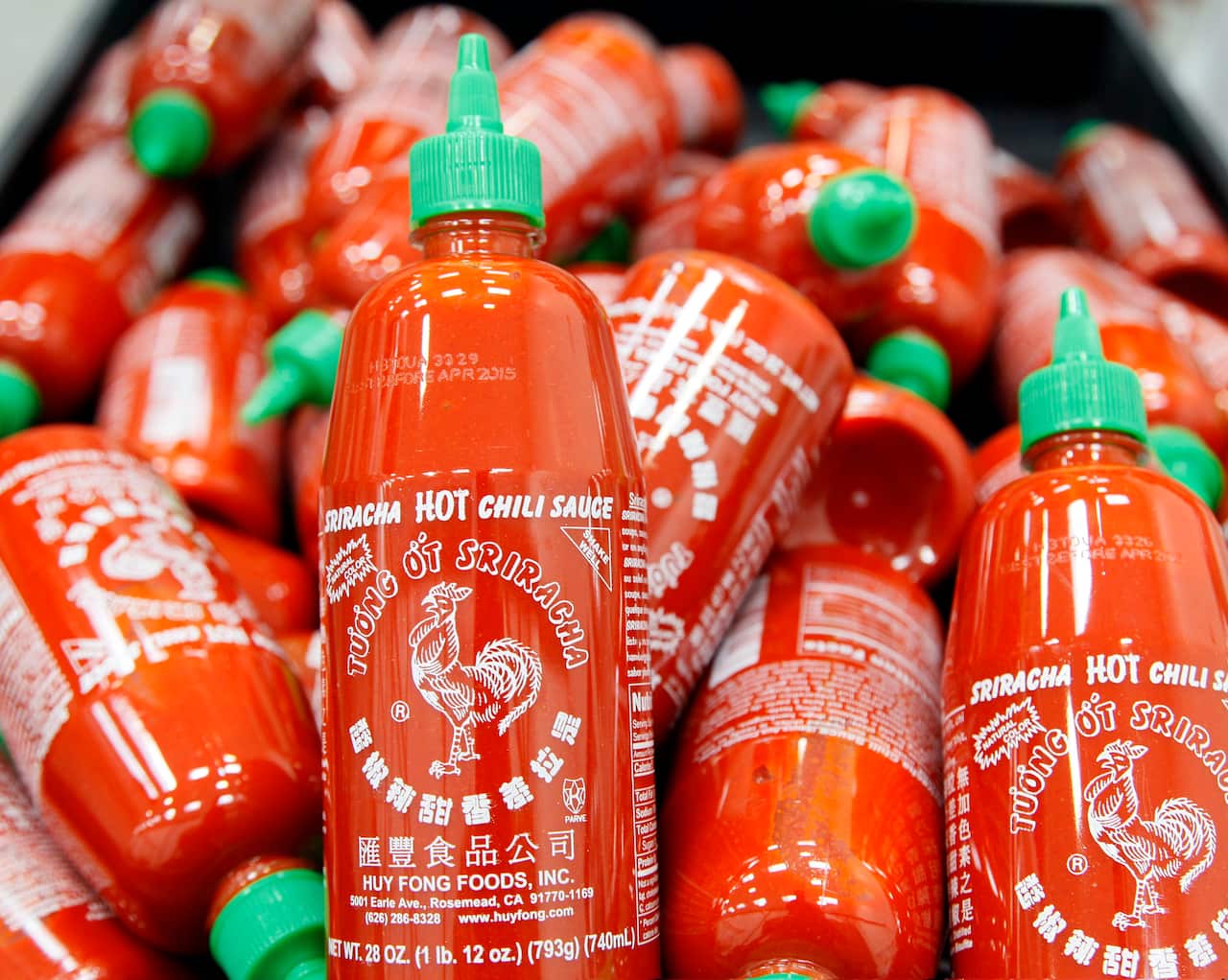 A pile of Sriracha bottles. 