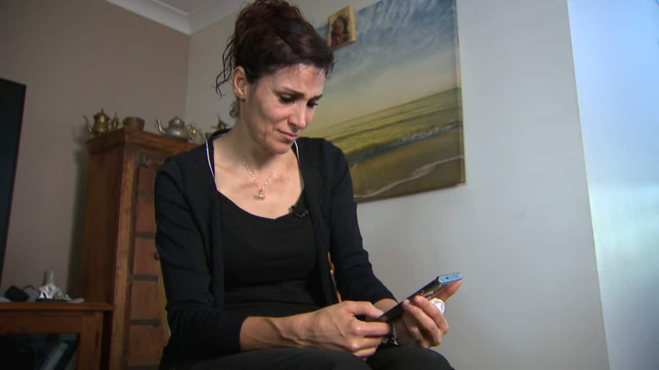 A woman looks at a phone and cries.