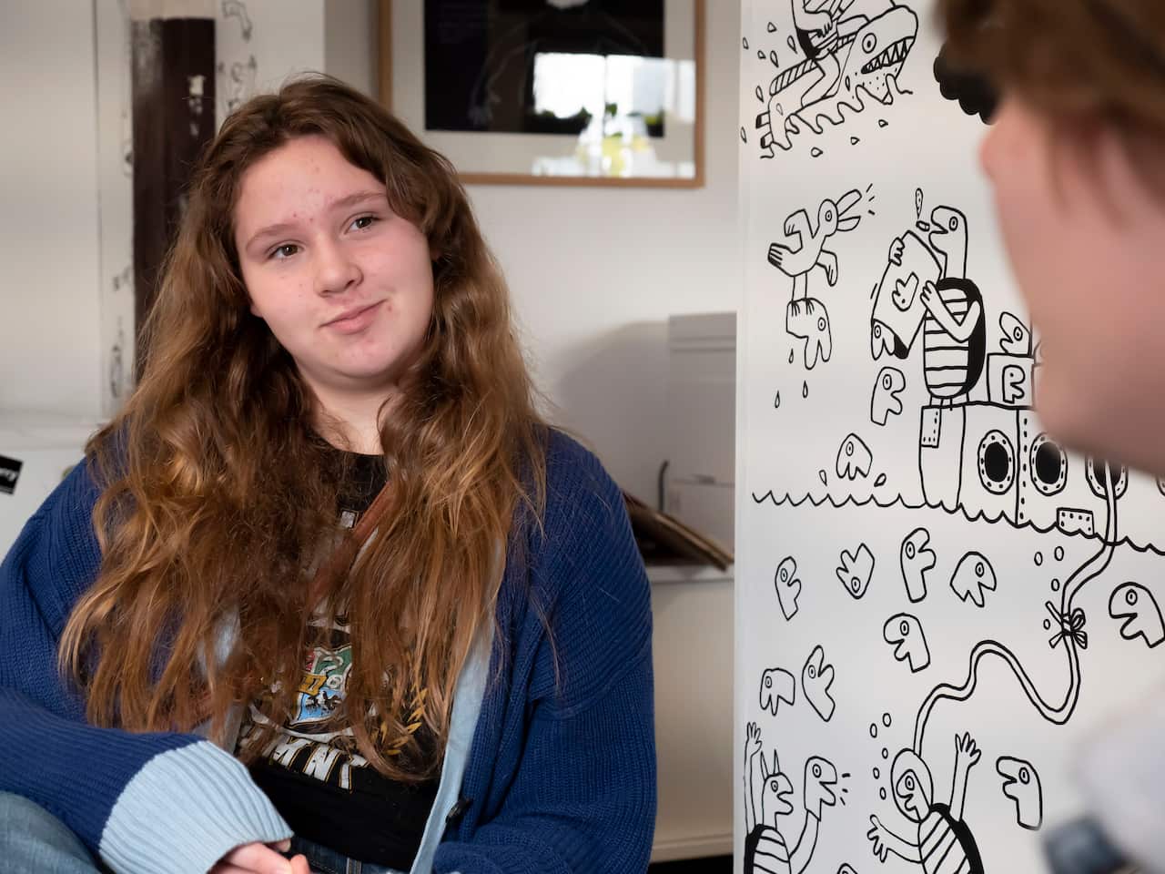 A teenage girl sitting and facing the camera