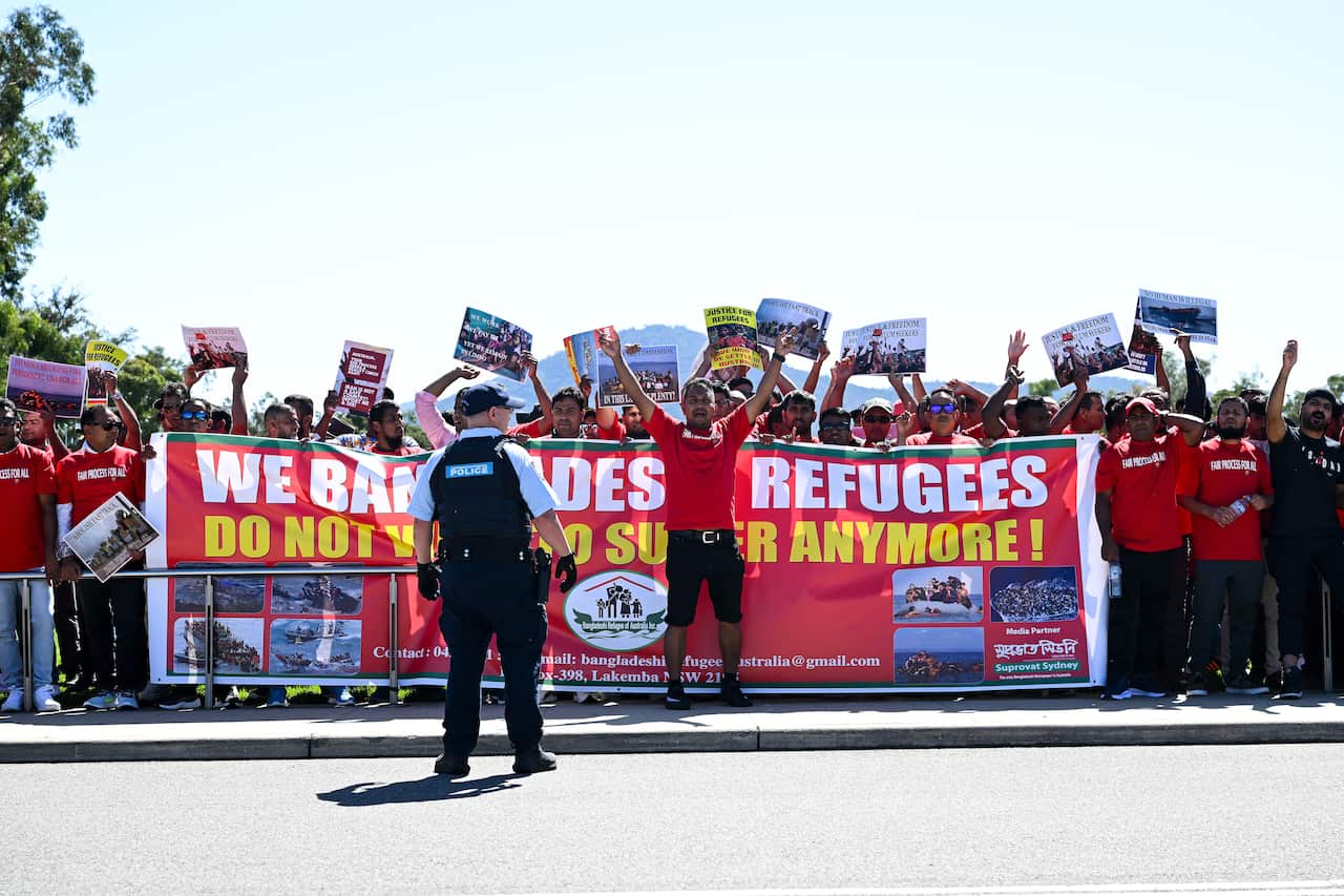 Police watch a group of protestors outside Parliament.