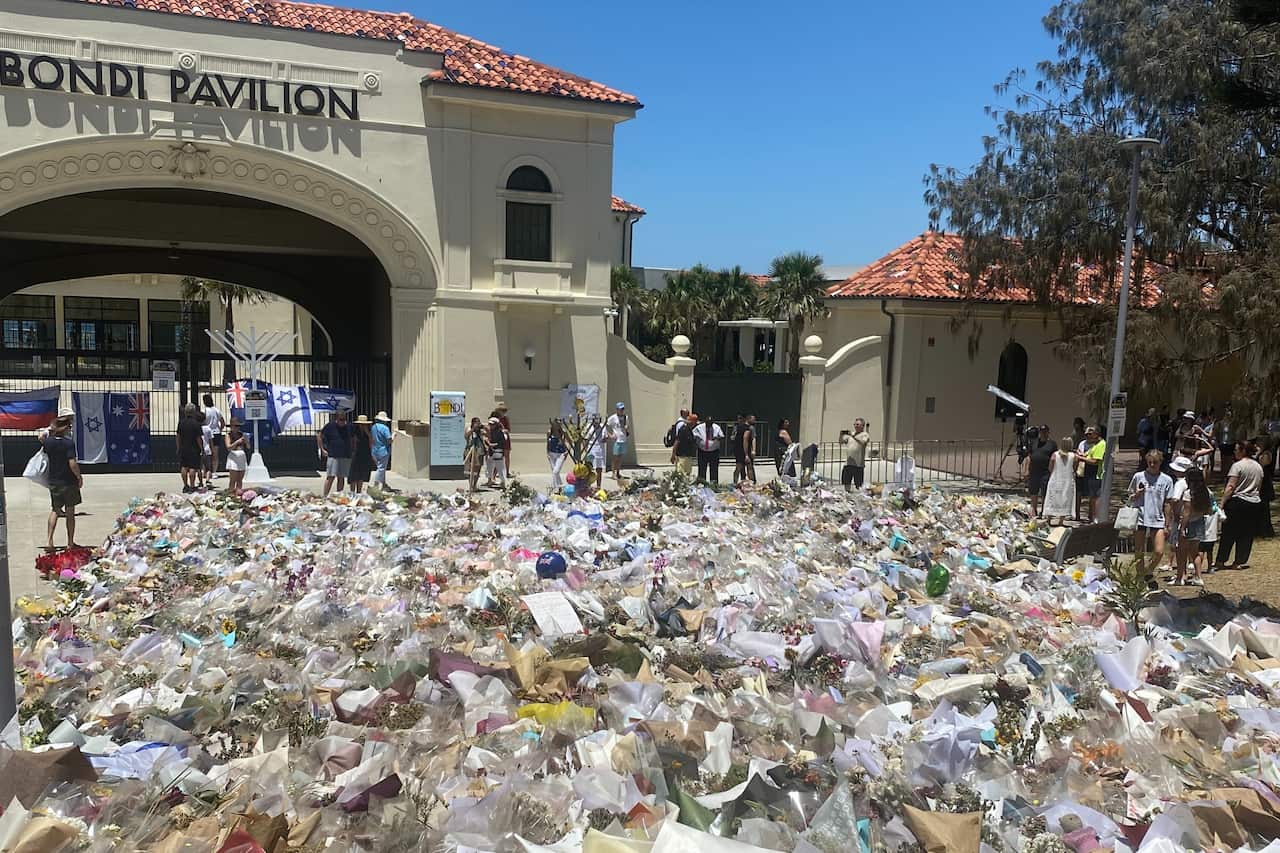 Hundreds of bunches of flowers in front of a beige building that has the sign Bondi Pavilion on it