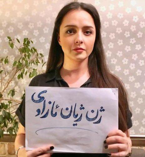 Woman holds paper with Persian script on it. 