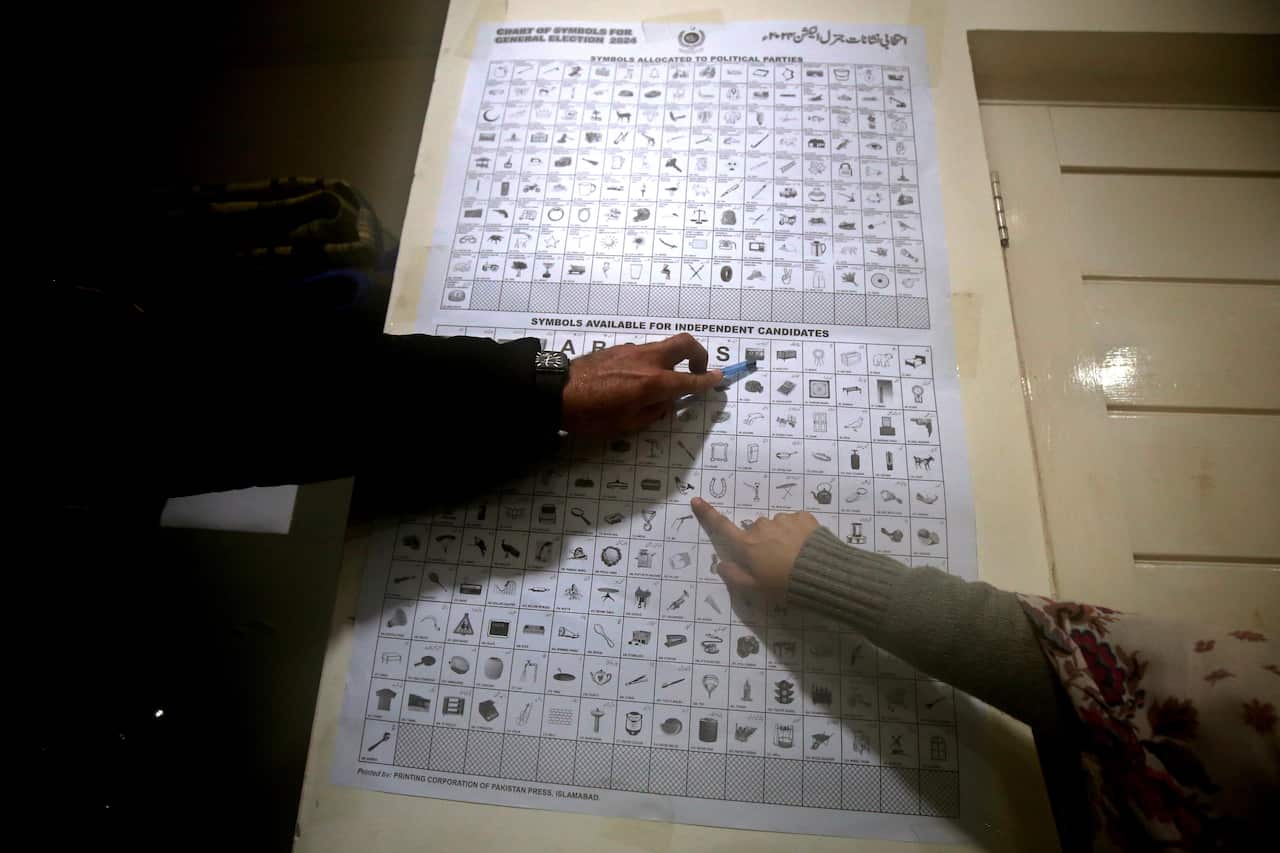 One person is pointing to a symbol in a list, while another person is pointing to a different symbol.