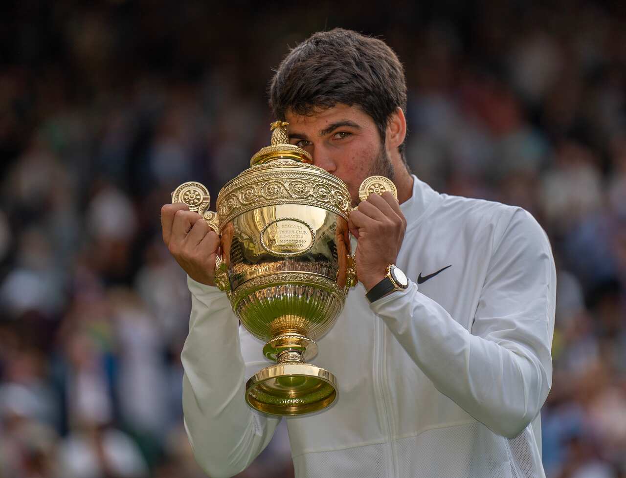 A man kisses the Wimbledon trophy.