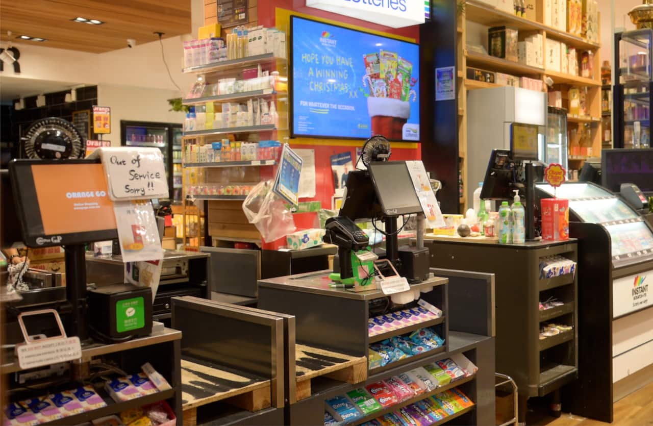 A wide shot of a supermarket check out area, showing self checkout scanners.