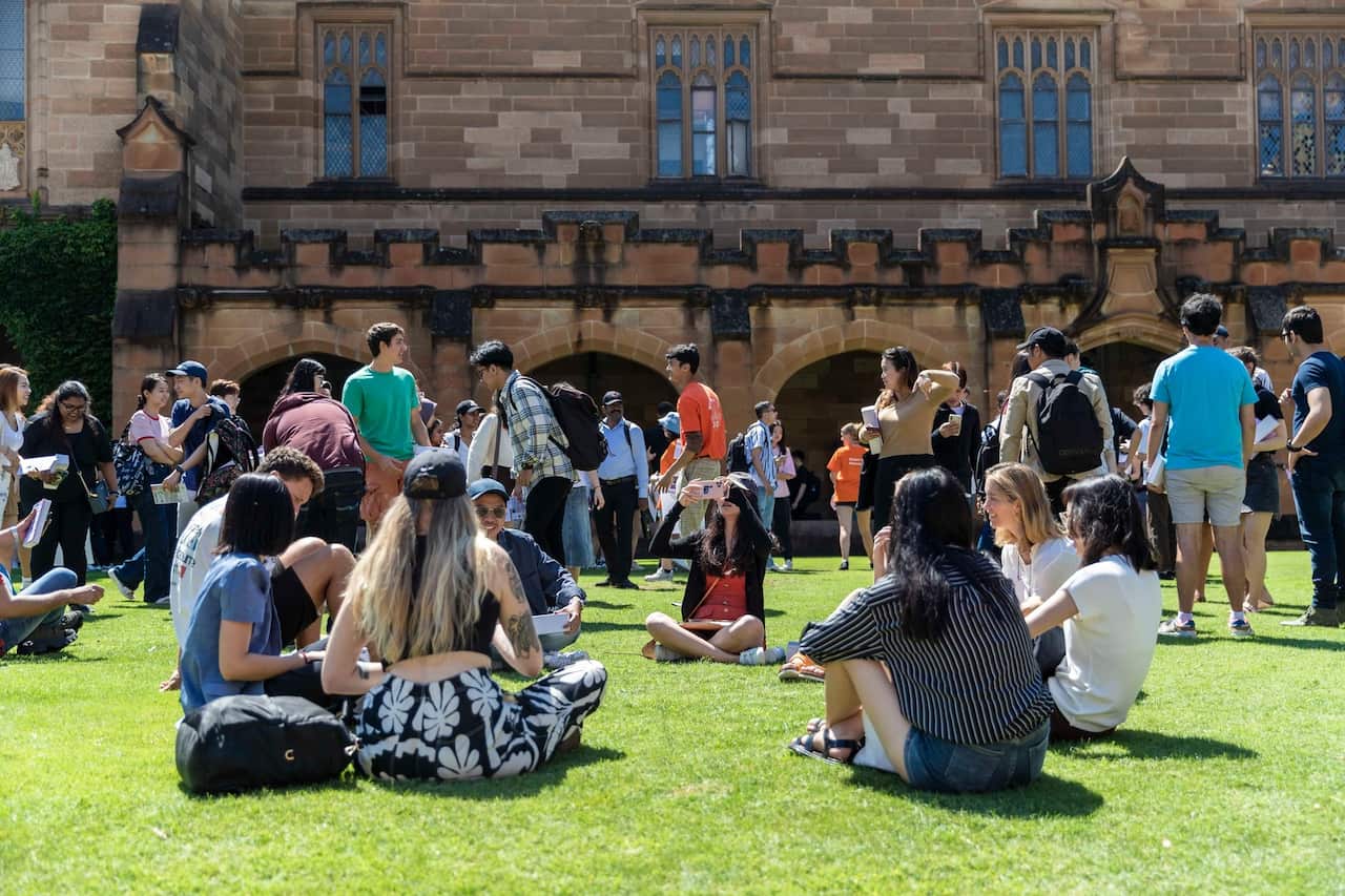 University of Sydney students sit on a lawn on campus.