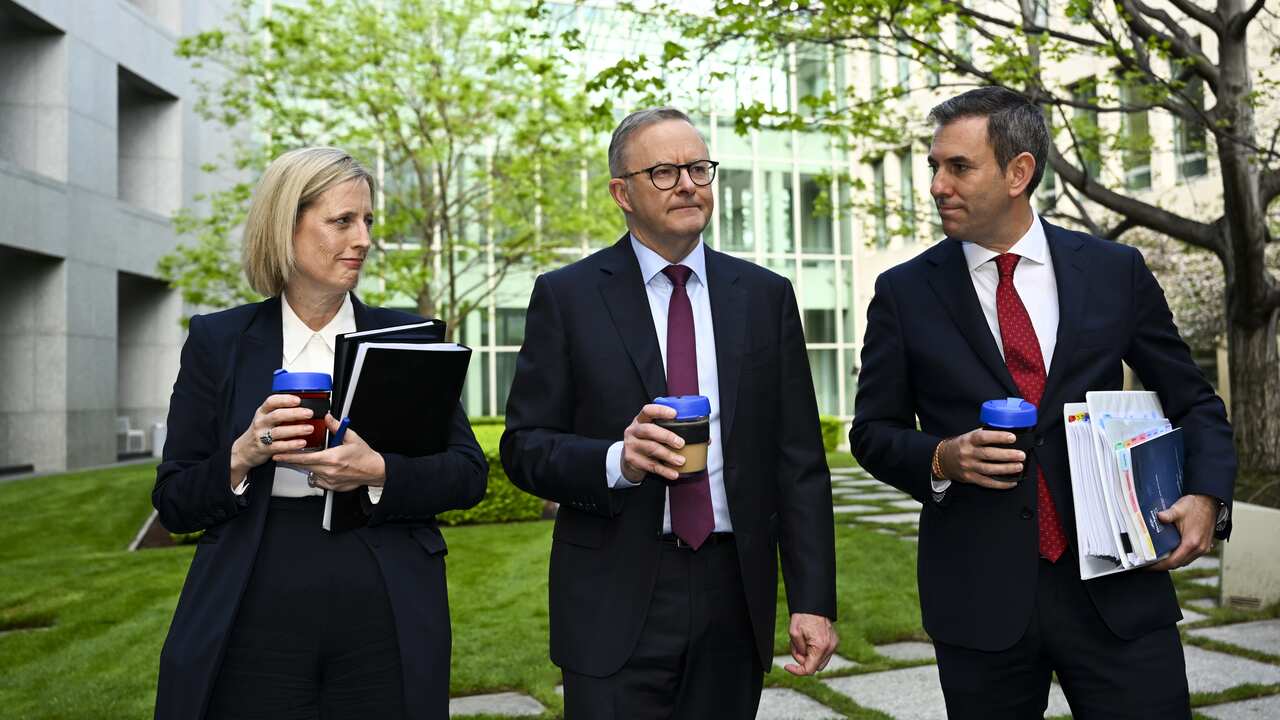 Australian Finance Minister Katy Gallagher, Australian Prime Minister Anthony Albanese and Australian Treasurer Jim Chalmers holding coffees and documents while speaking in Parliament House courtyard.