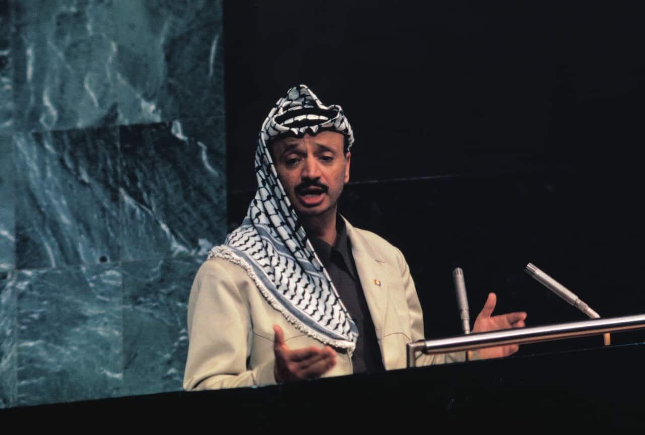 A younger Arab man wearing a keffiyeh and a beige garment, addressing the United Nations General Assembly