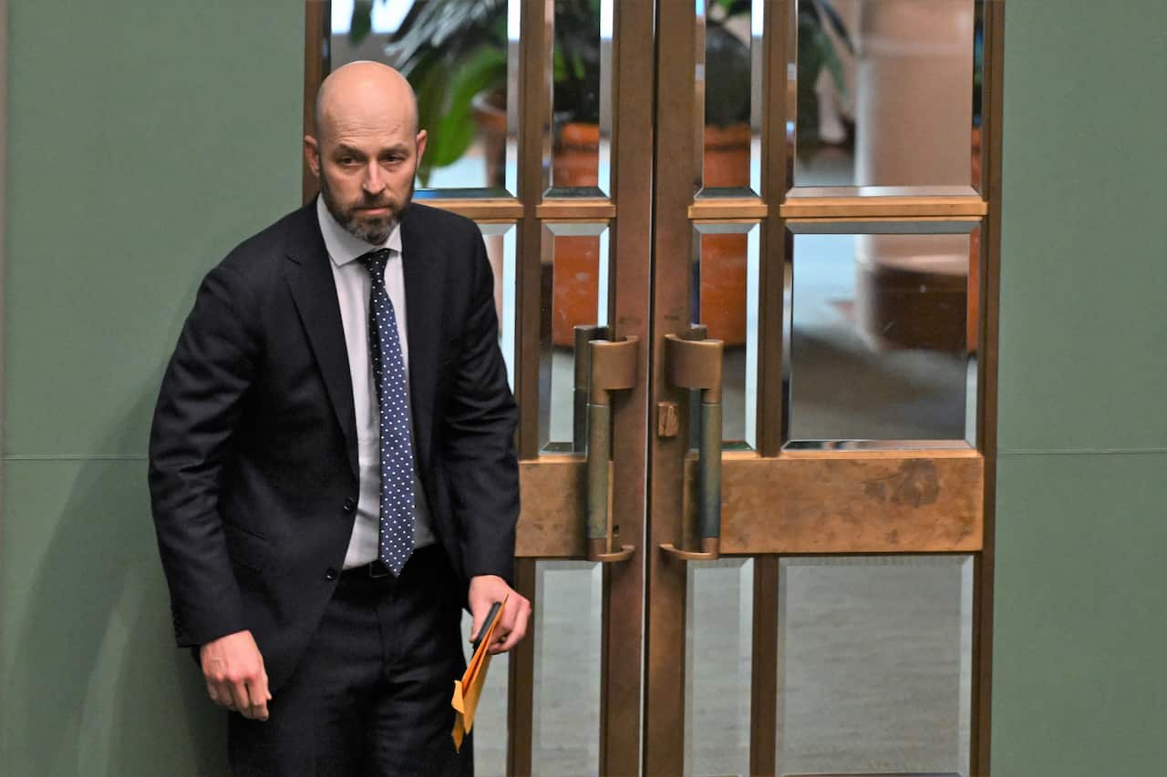 A man in a suit standing next to some heavy glass-panelled doors