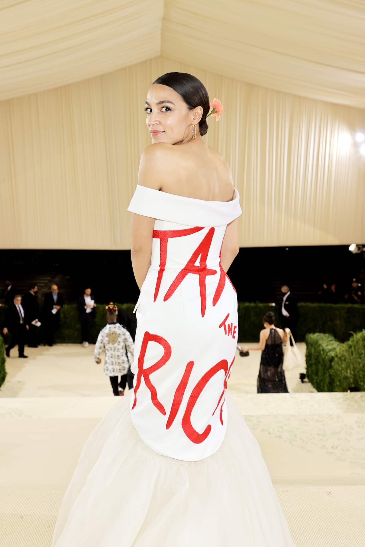 Woman turns around in white dress with red text on it: "tax the rich".