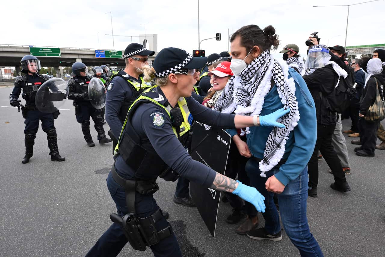 A group of protesters clashing with police on a road.