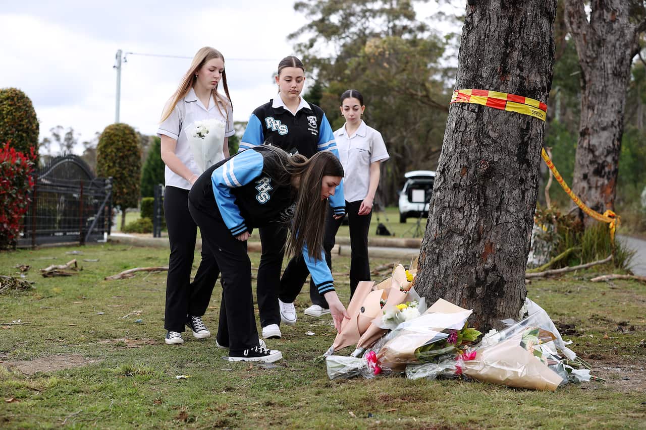 Teenagers place flowers underneath a tree 