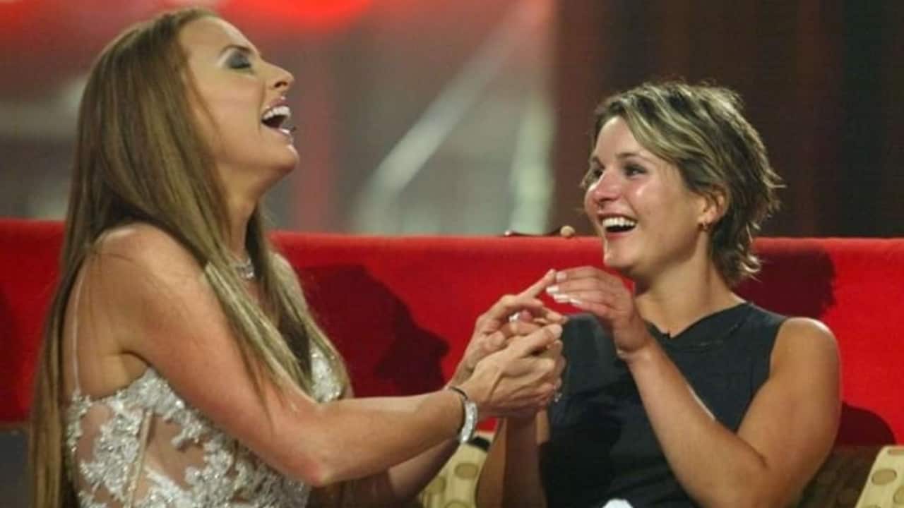 two young women laughing holding hands on a red couch