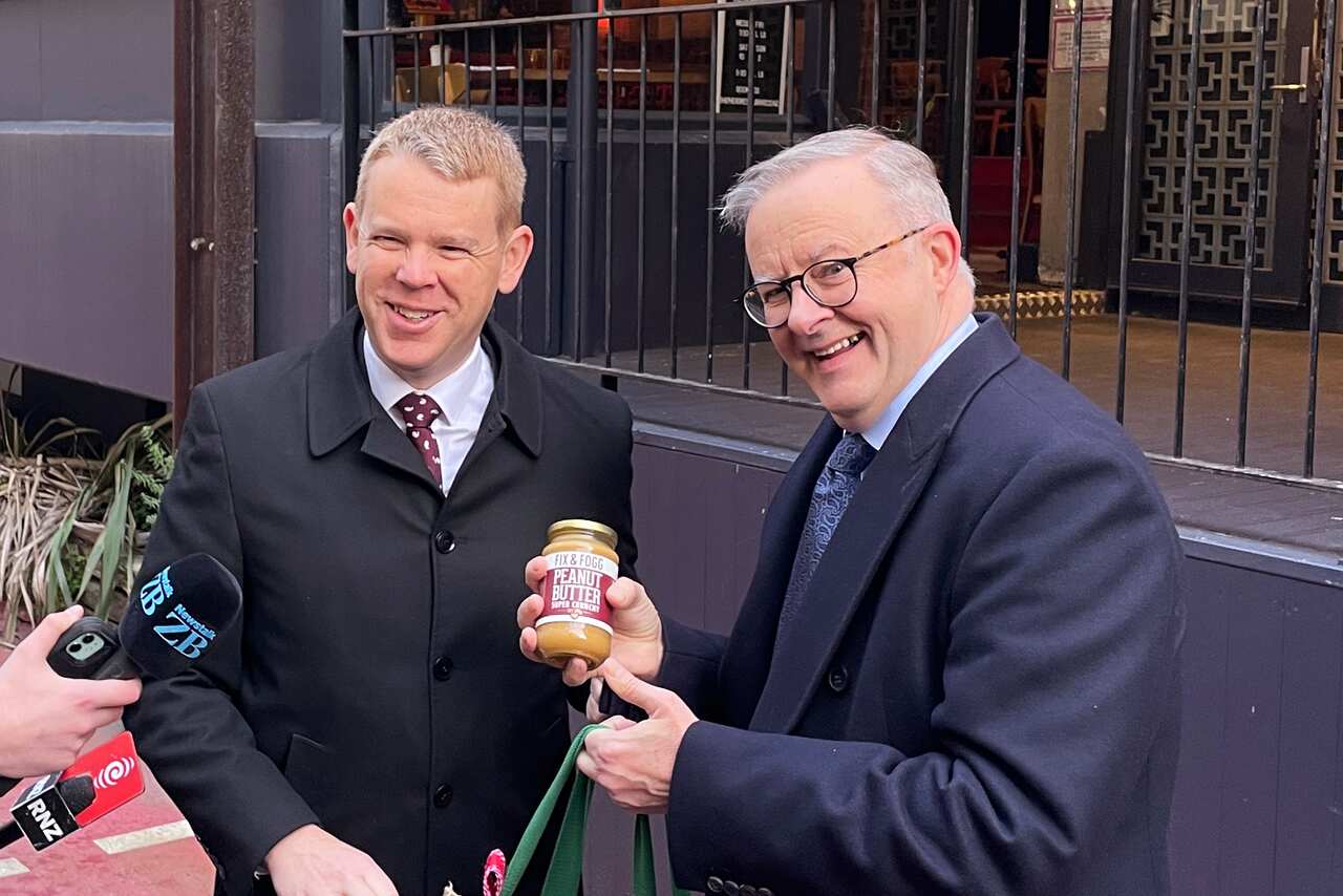 Two men in suits smiling.