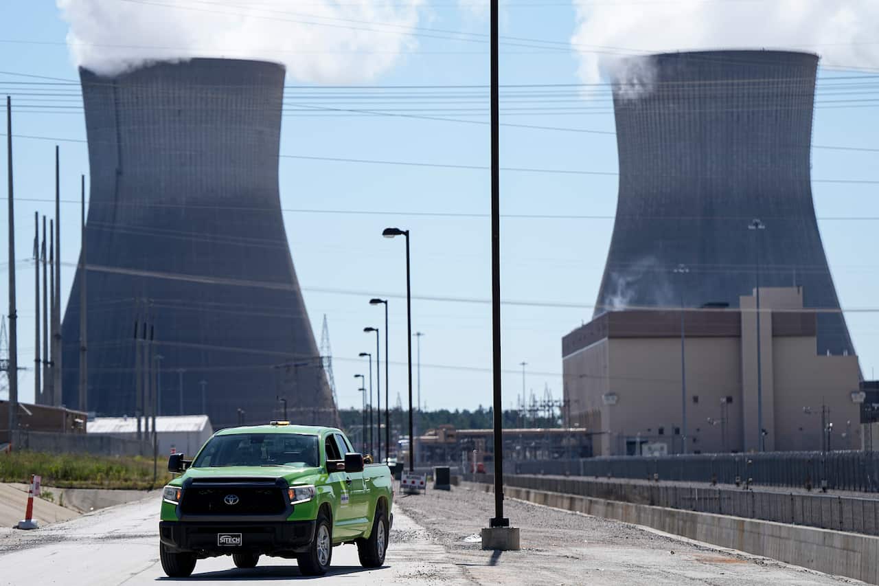 Two reactors at a nuclear plant. A green car is parked far in front of them.