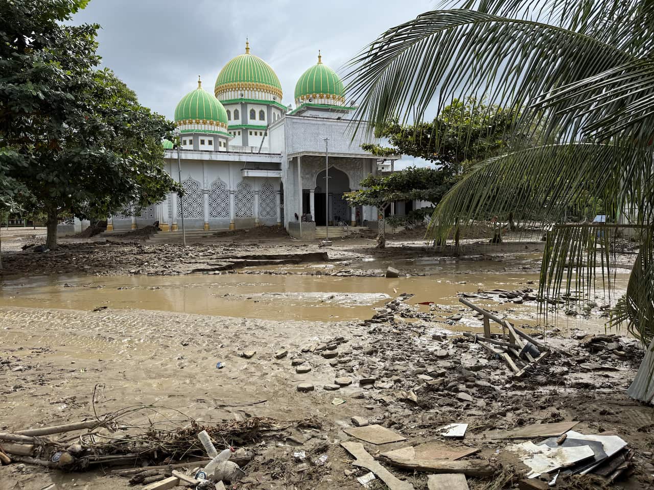 An Indonesian mosque site is covered in mud and flood debris
