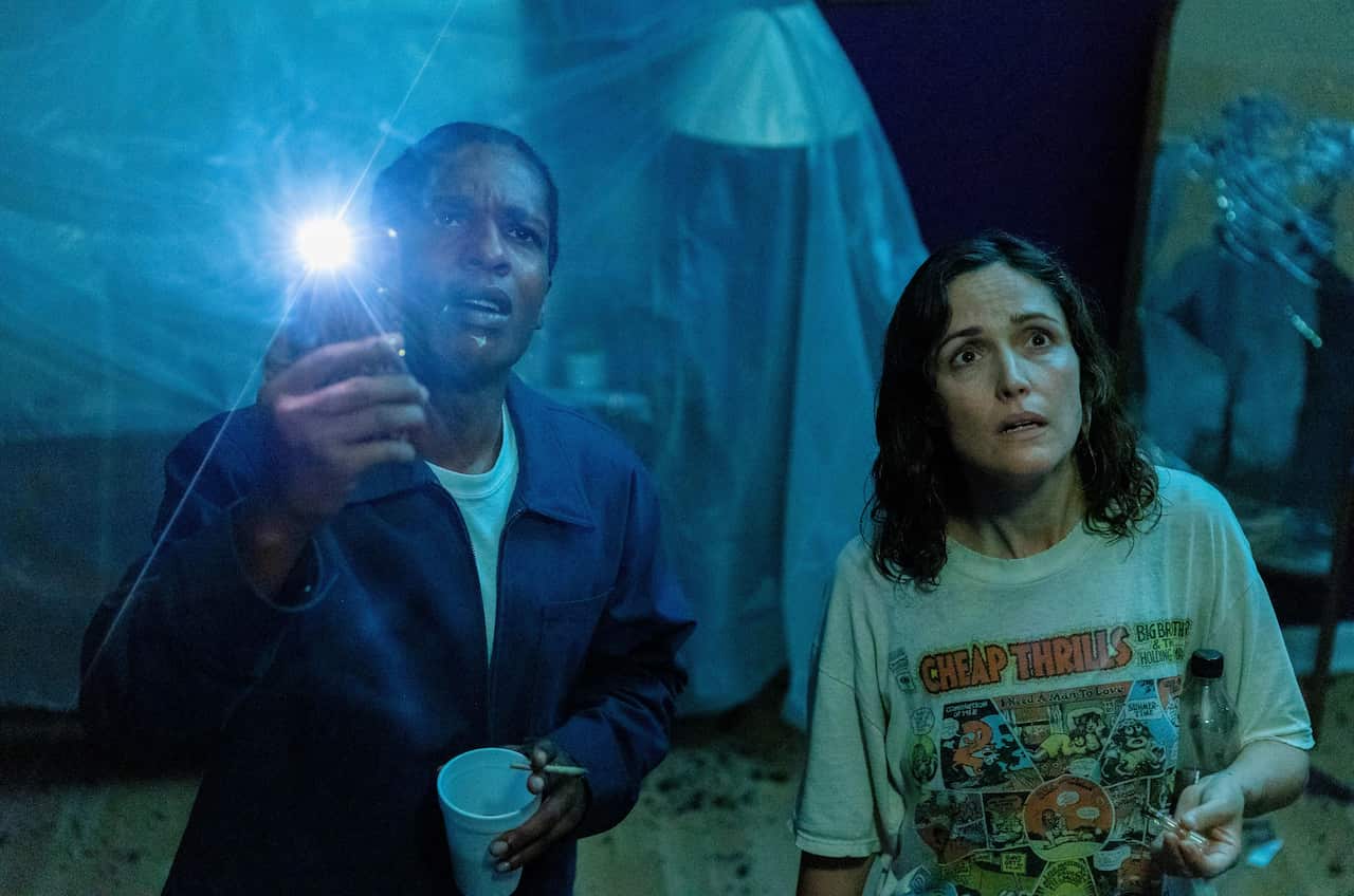 A man and woman in a dark room. The man is shining a torch at something on the ceiling.