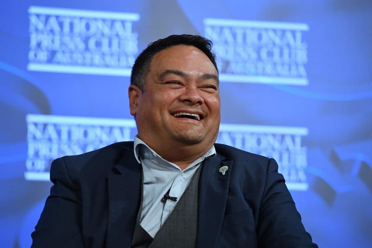 A man in a suit sitting and laughing 