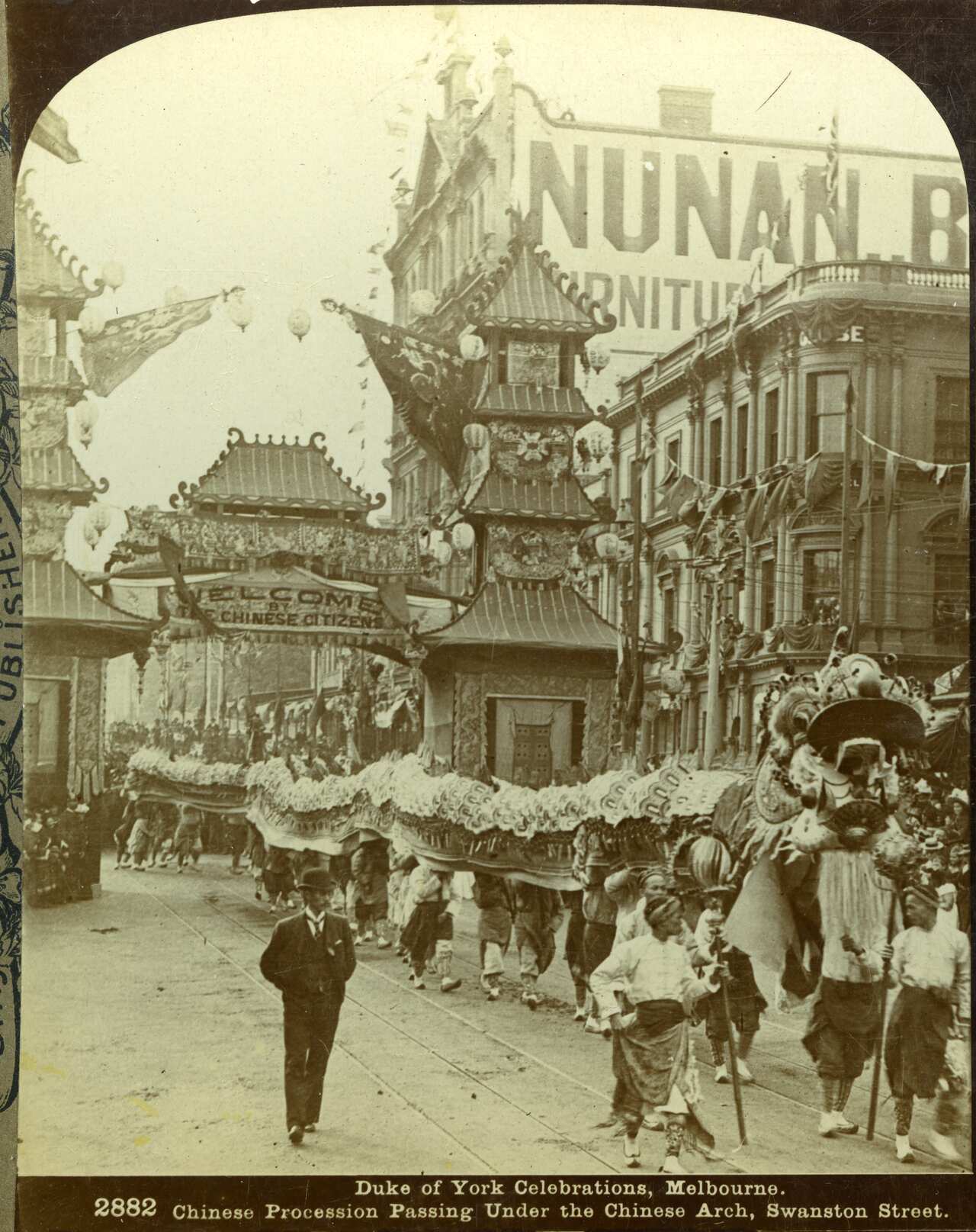 A black and white photo of a Chinese dragon parading through a street