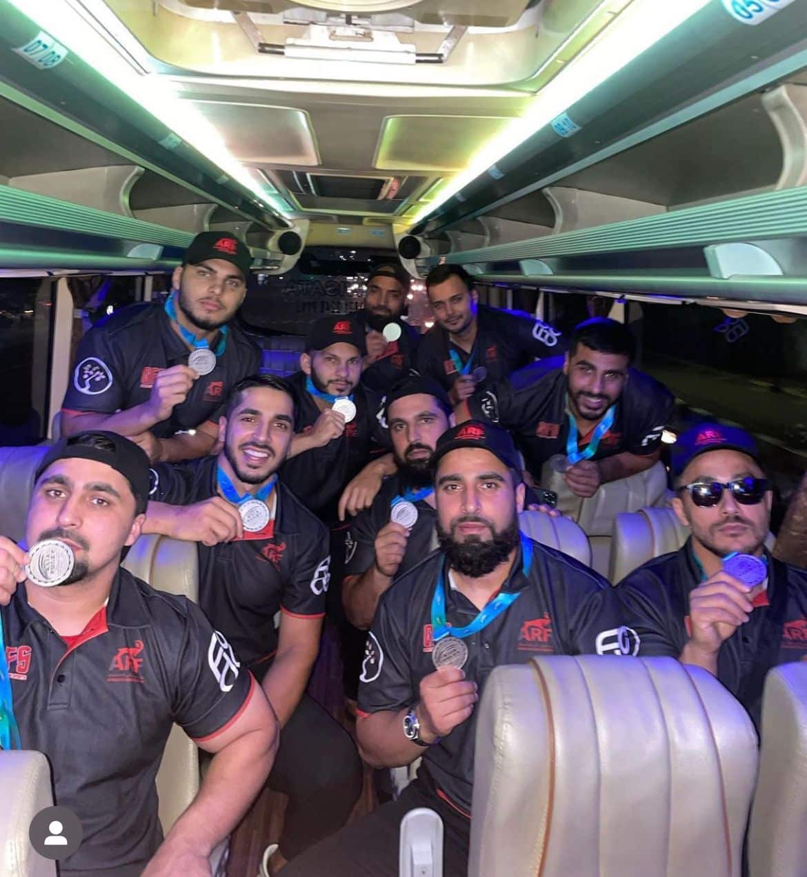 A group of men carry their silver medals on a bus 