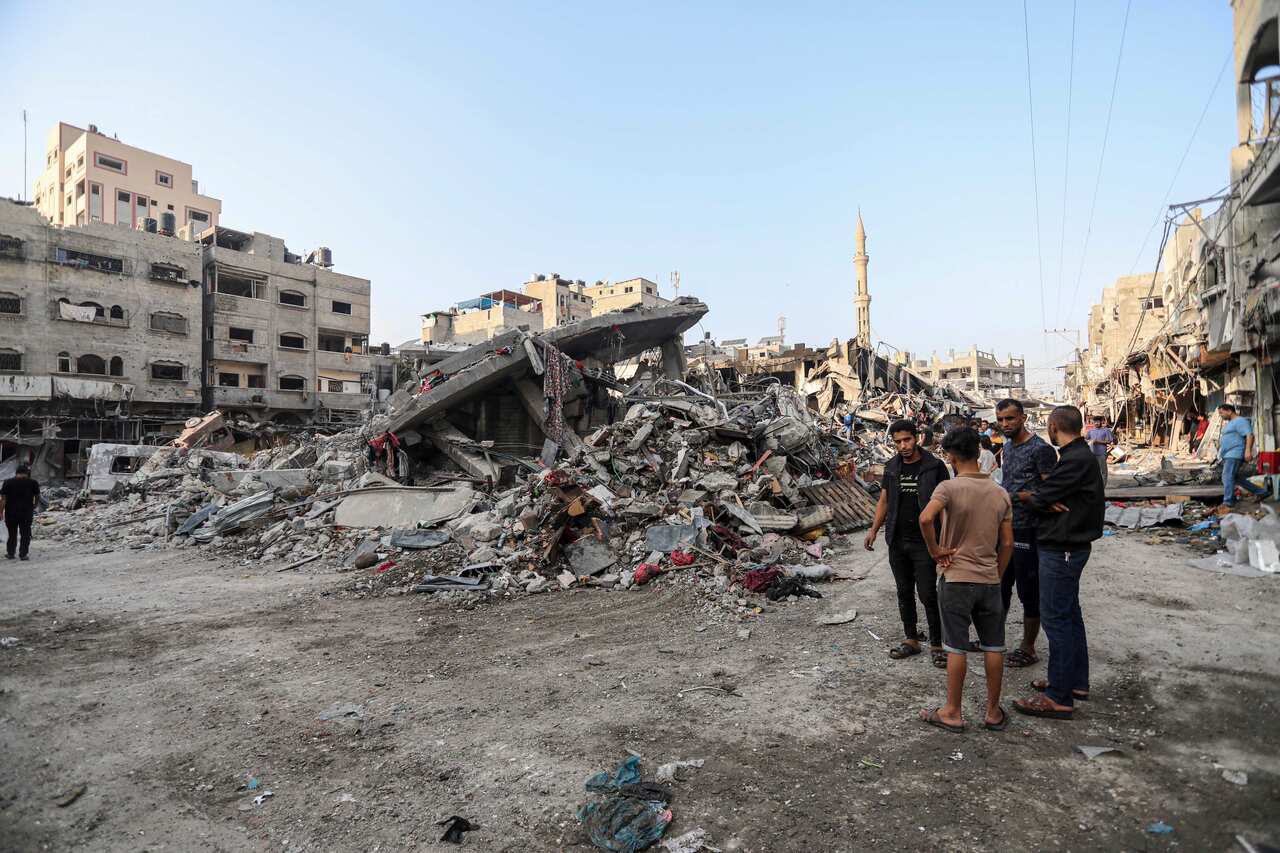 A group of men standing next to a destroyed building.