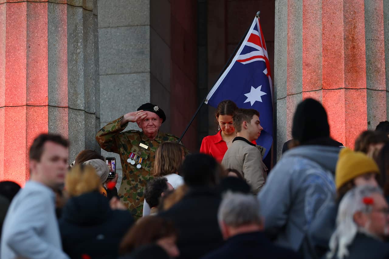 People gathering as a man in soldier's uniform salutes in the background