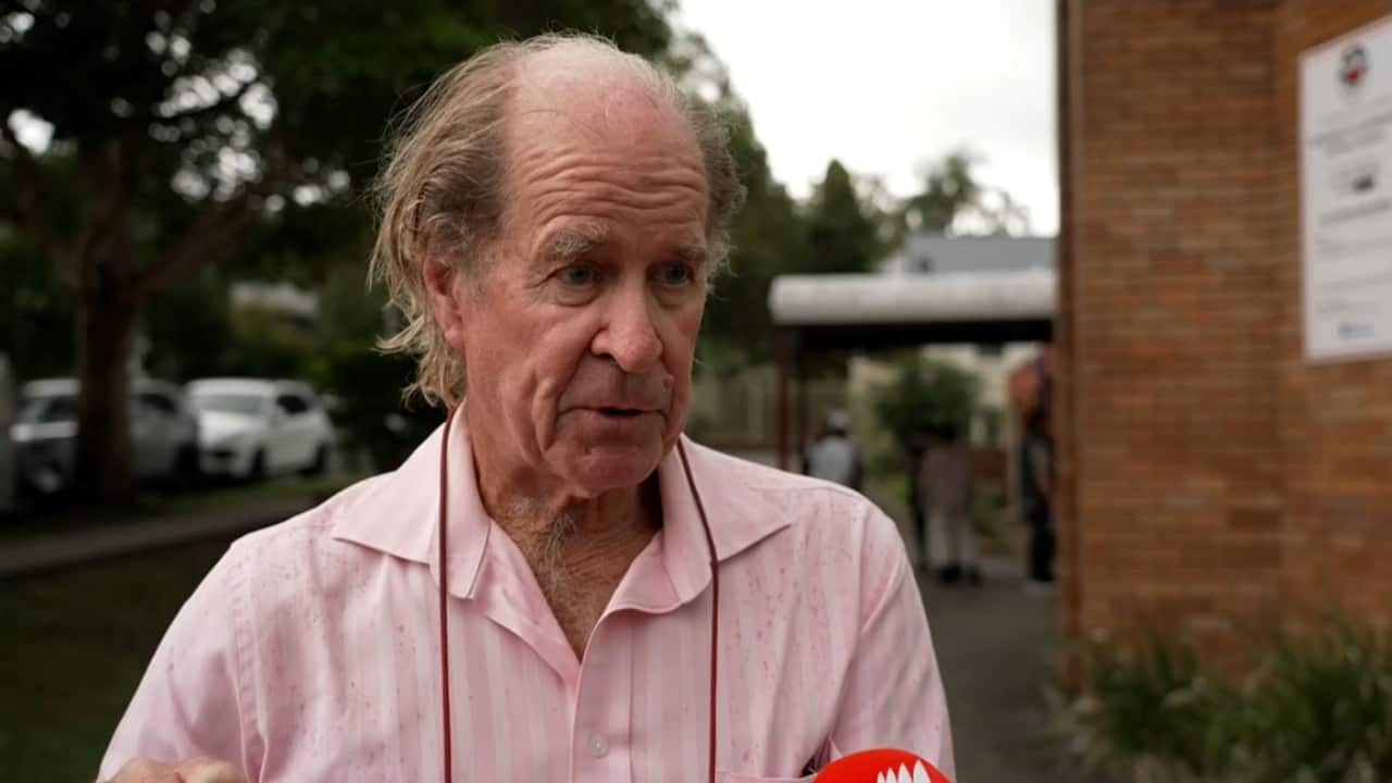 An older white man wearing a pink button-up shirt