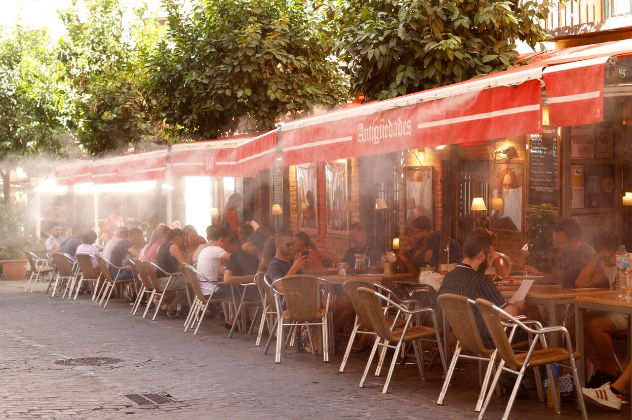 People sitting at a bar cooled by water vapour during a heatwave.