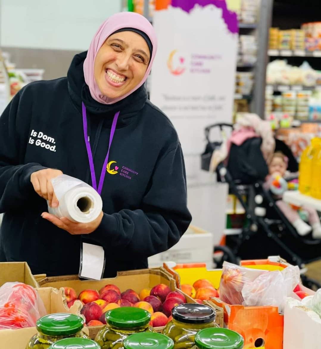 Woman smiles while packing fruit in plastic bags